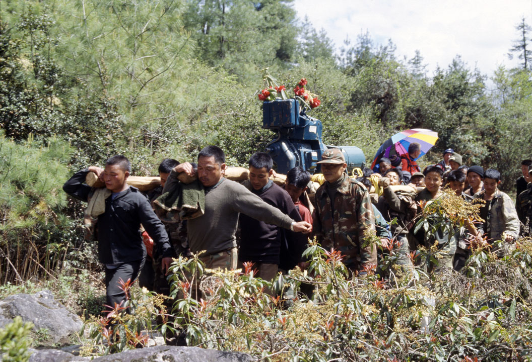 b_464m trek6.jpg - Bhoutan - Dochu La, Hongtso sur le sentier, rencontre insolite avec un groupe qui transporte un moteur de groupe électrogène décoré de fleurs de rhododendrons : ils ont ansi fait une bonne dizaine de km..